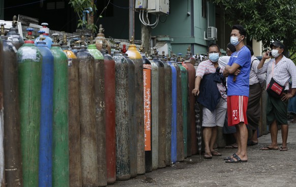 epa09336866 Myanmar people wait near oxygen tanks lined up to refill outside an oxygen factory in Yangon, Myanmar, 11 July 2021. Myanmar is facing a shortage of oxygen supplies to treat critical patie ...