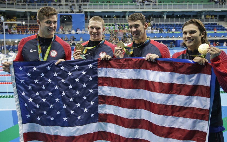Nathan Adrian, Ryan Murphy, Michael Phelps and Cody Miller hold their national flag during the victory lap after winning gold in the men&#039;s 4 x 100-meter medley relay final during the swimming com ...