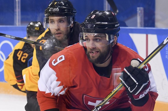 Thomas Ruefenacht of Switzerland, right, fights for the puck with Daryl Boyle of Germany, during the men ice hockey play-off qualification match between Switzerland and Germany in the Kwandong Hockey  ...