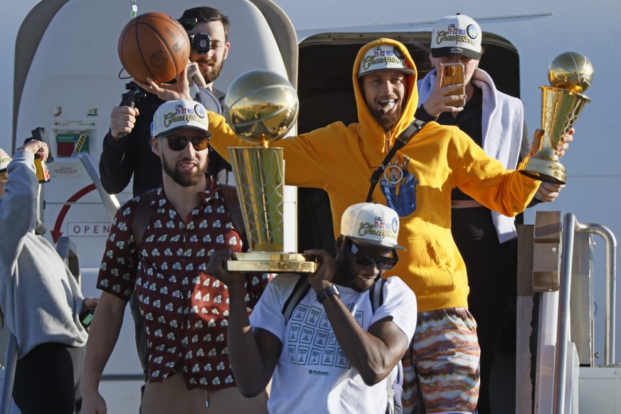 The Golden State Warriors, including Stephen Curry, holding his NBA Finals MVP trophy; Klay Thompson, left; and Draymond Green, holding the Larry O&#039;Brien Championship Trophy, step off a plane at  ...