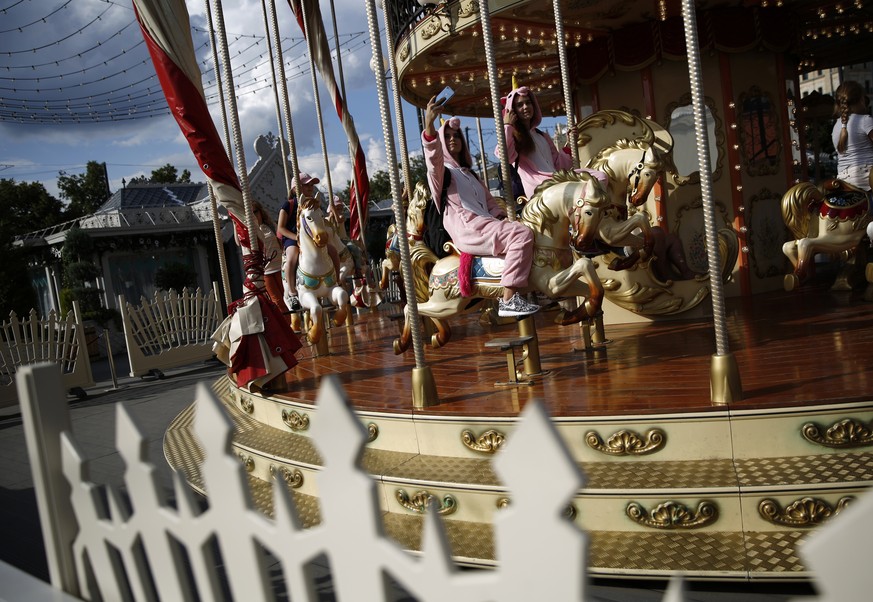 Girls in costumes ride a carousel near Red Square during the 2018 soccer World Cup in central Moscow, Russia, Friday, July 13, 2018. (AP Photo/Rebecca Blackwell)