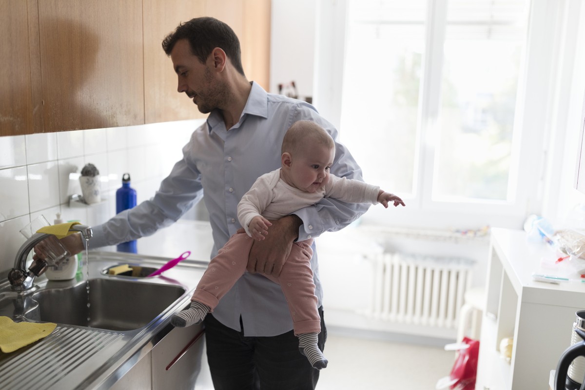ARCHIV  ZUM THEMA VATERSCHAFTSURLAUB STELLEN WIR IHNEN FOLGENDES BILDMATERIAL ZUR VERFUEGUNG -- A father holds his his five-month-old daughter on his arm while pouring himself a glass of water, pictu ...