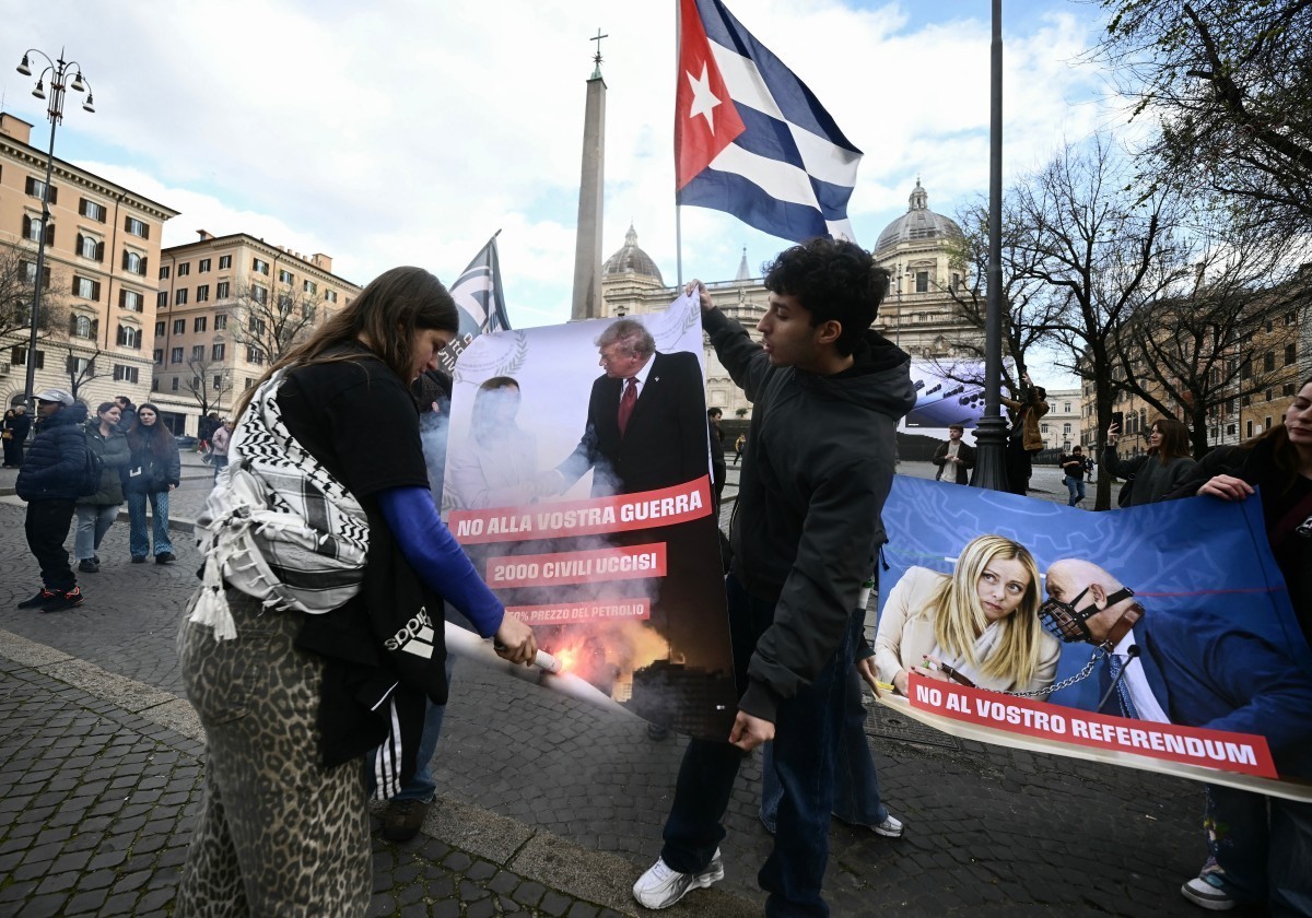 Demonstrators burn a poster depicting Italy's Prime Minister Giorgia Meloni and US president Trump while taking part in a rally organized by the "Social No" commitee to denounce the war ...