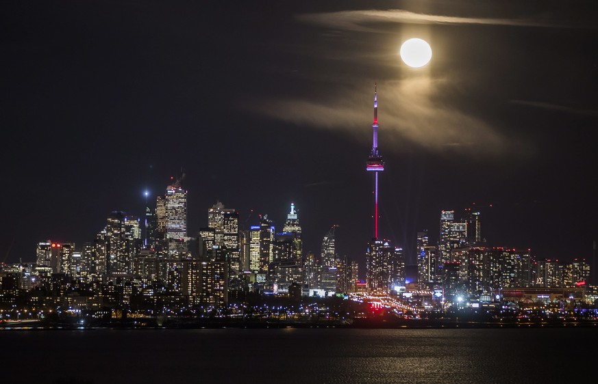 The moon rises behind the skyline in Toronto, Friday Jan. 13, 2017. (Mark Blinch/The Canadian Press via AP)