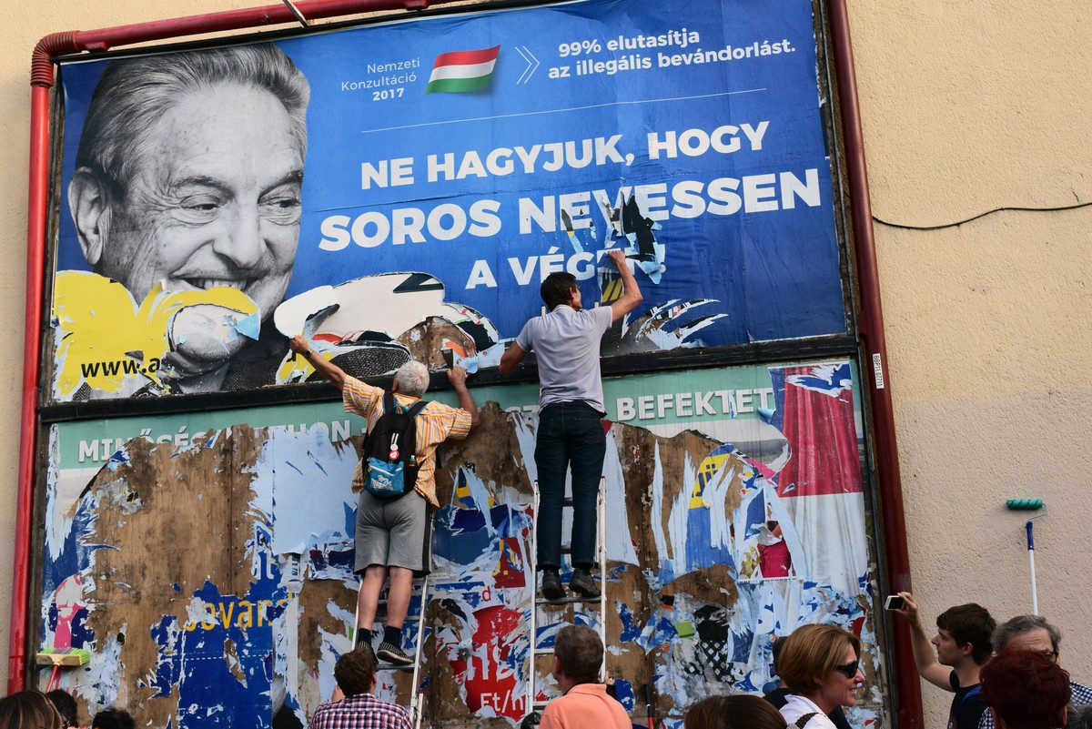 Activists from the Egyutt (Together) party tear down an ad by the Hungarian government against George Soros, in Budapest, Wednesday, July 12, 2017. The Hungarian government said Wednesday it will soon ...