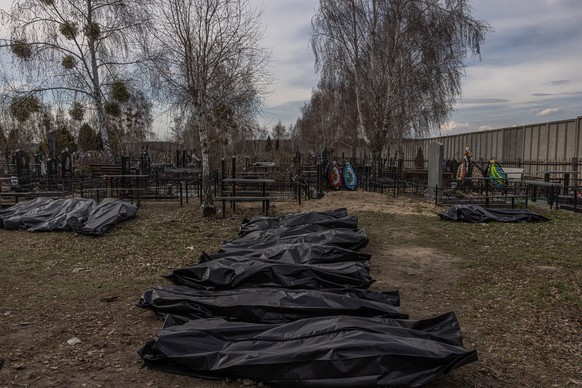 epa09876893 Bodies of killed people, which were brought to the cemetery, lay on the ground in body bags, in Bucha, northwest of Kyiv, Ukraine, 07 April 2022. Hundreds of tortured and killed civilians  ...