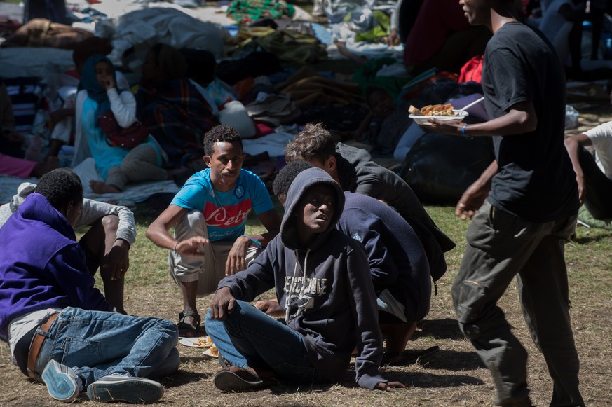 Fluechtlinge essen ein von freiwilligen Helfern der Tessiner Hilfsgruppe Associazione Firdaus verteiltes Abendessen, in einem Park in der Naehe des Bahnhofs in Como am Donnerstag, 12. August 2016, in  ...