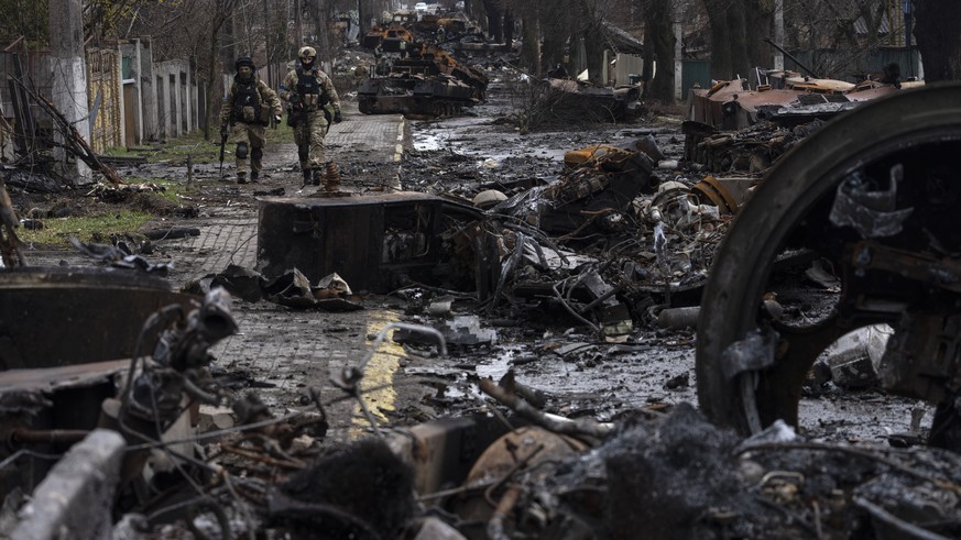 Soldiers walk amid destroyed Russian tanks in Bucha, on the outskirts of Kyiv, Ukraine, Sunday, April 3, 2022. (AP Photo/Rodrigo Abd)