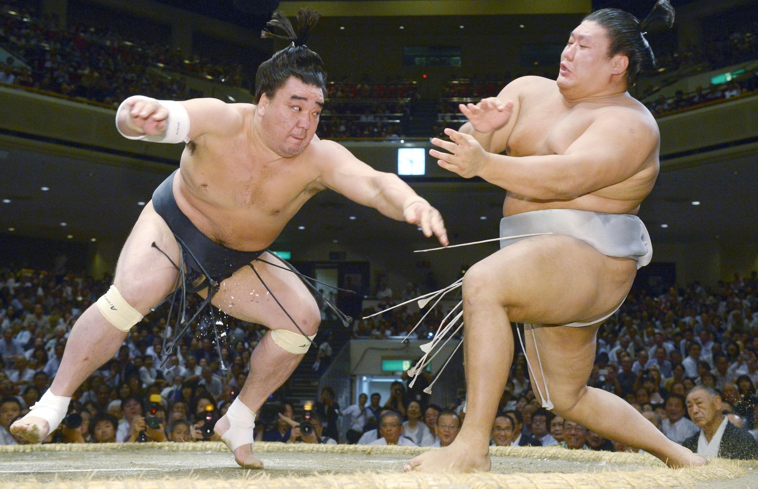 In this Sept. 16, 2016, photo, Mongolian sumo grand champion Harumafuji, left, pushes opponent Takanoiwa out of the ring to win their bout at the Autumn Grand Sumo Tournament in Tokyo. Japanese media  ...