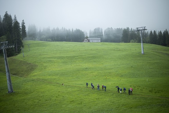 Wanderer mit Schirm im Regen, am Dienstag, 29. Juli 2025, in Wildhaus. (KEYSTONE/Gian Ehrenzeller)