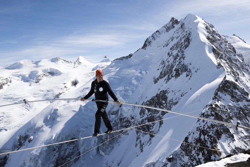epa04671589 Swiss tightrope artist Freddy Nock walks on a rope towards Piz Prievlus, with the Piz Bernina and Biancograt ridge in the background, in Graubuenden, eastern Switzerland, 20 March 2015. He ...