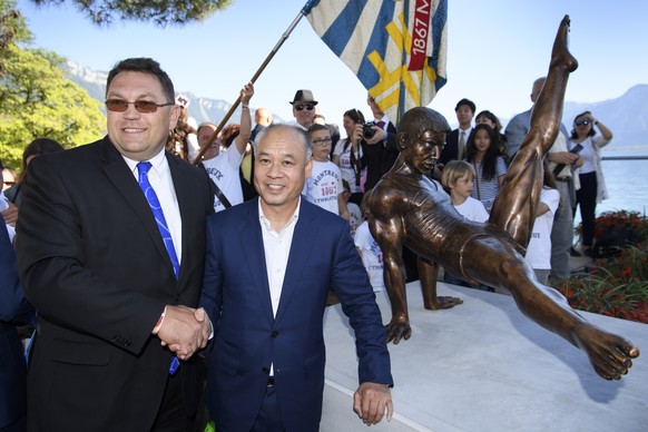 China&#039;s Li Ning, right, Olympic champion of artistic gymnastics, shakes hands with the mayor of the city of Montreux Laurent Wehrli, left, in front of a statue of him during the unveiling ceremon ...