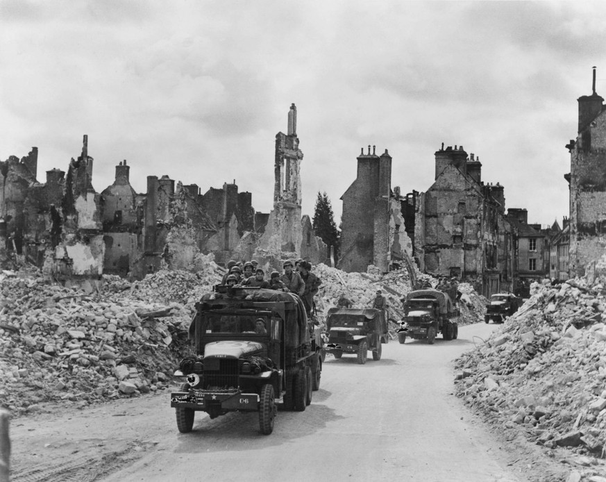 Trucks, some with U.S. soldiers standing in back, riding through the ruins Valognes, France. June-July 1944. Normandy Campaign, World War 2. BSLOC20142129 Courtesy Everett Collection PUBLICATIONxINxGE ...