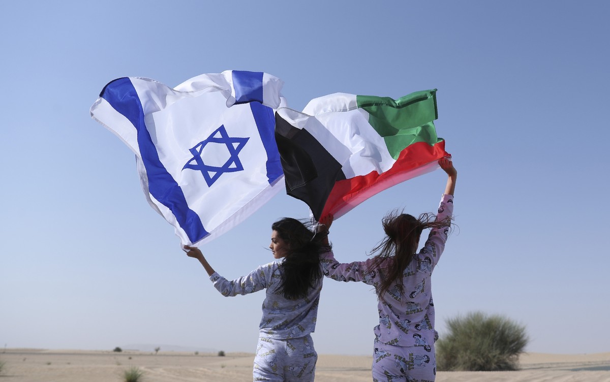 Israeli model May Tager, left, holds Israel's blue-and-white flag bearing the Star of David while next to her Anastasia Bandarenka, a Dubai-based model originally from Russia, waves the Emirati f ...
