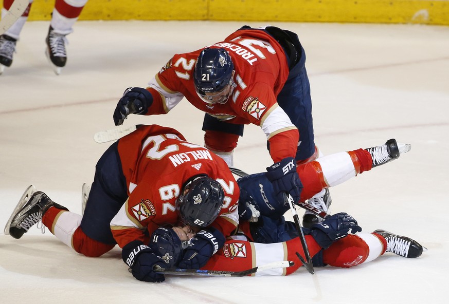 Florida Panthers centers Denis Malgin (62) and Vincent Trocheck (21) pile on top of left wing Jonathan Huberdeau after Huberdeau scored the game winning goal during the third period of an NHL hockey g ...