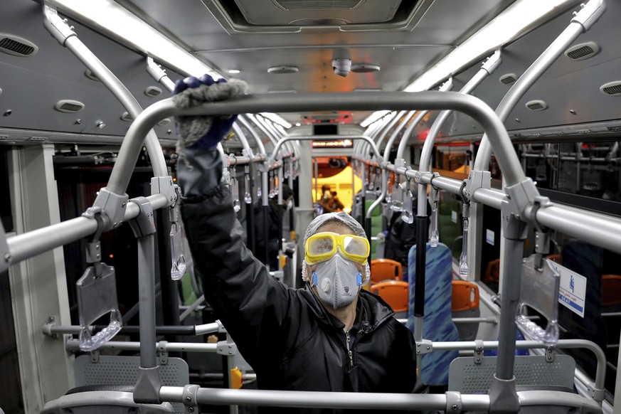 A worker disinfects a public bus against coronavirus in Tehran, Iran, in early morning of Wednesday, Feb. 26, 2020. Iran's government said Tuesday that more than a dozen people had died nationwid ...