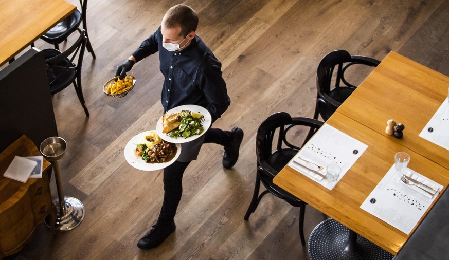 epa08414864 A waiter of the &#039;La Brasserie de Montbenon&#039; restaurant serves dishes to guests, Lausanne, Switzerland, 11 May 2020. Restaurants, shops, markets, museums and libraries reopened un ...