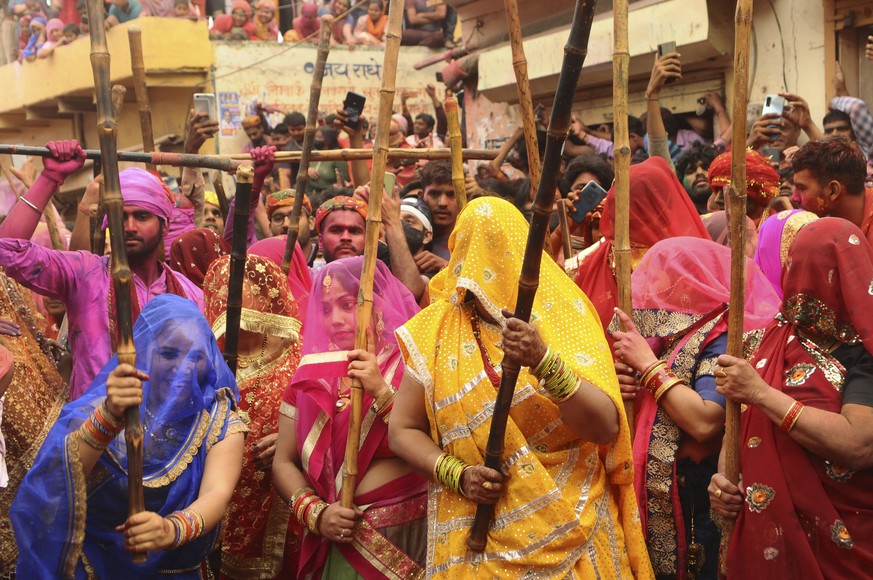 Indian women from Barsana village beat villagers from Nandgoan with wooden sticks as they tease them during Lathmar holi festival celebrations at the legendary hometown of Radha, consort of Hindu God ...
