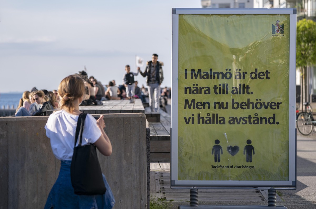 People enjoy the warm evening weather in Malmo, Sweden, Tuesday May 26, 2020 as a sign reads 'In Malmo everything is near. But now we need to keep a distance'. Sweden has defended its respon ...