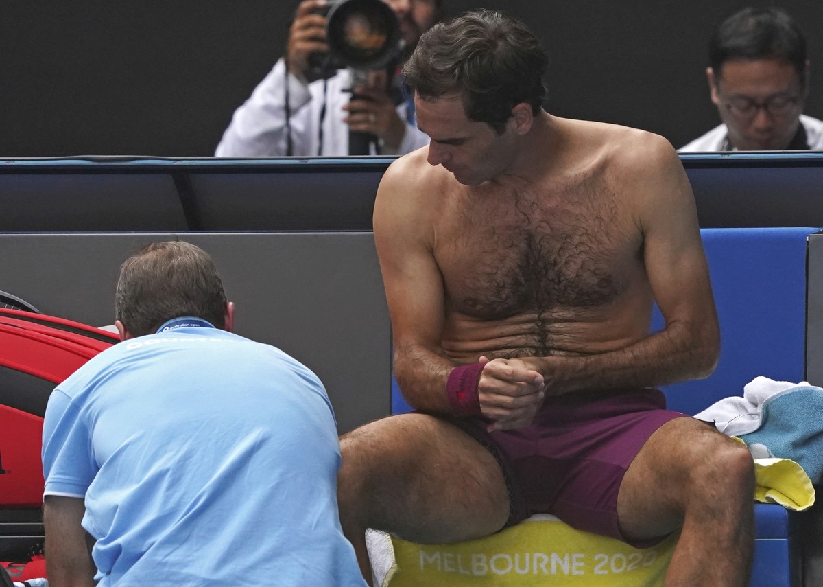 Switzerland's Roger Federer receives treatment from a trainer during his quarterfinal against Tennys Sandgren of the U.S. at the Australian Open tennis championship in Melbourne, Australia, Tuesd ...
