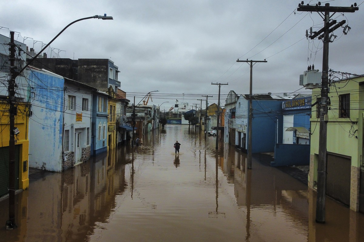 A man wades through an area flooded by heavy rains, in Porto Alegre, Rio Grande do Sul state, Brazil, Friday, May 3, 2024. (AP Photo/Carlos Macedo)