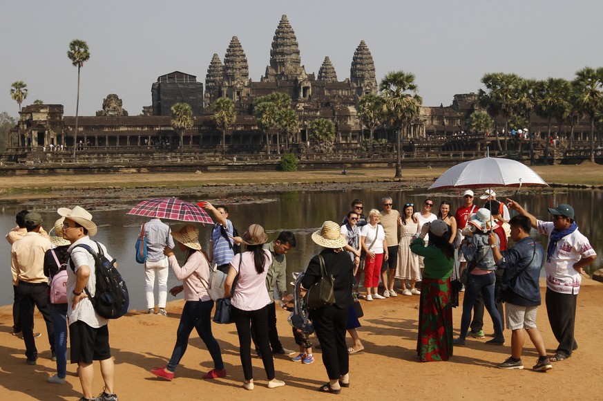 epa05799338 Tourists pose for the pictures at the Angkor Wat temple in Siem Reap province, Cambodia, 17 February 2017. The Cambodian Government has almost doubled the entrance fee to visit the Angkor  ...