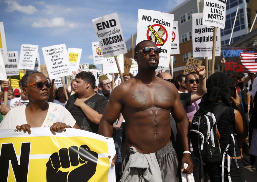 Demonstrators hold placards during a march by various groups, including &quot;Black Lives Matter&quot; and &quot;Shut Down Trump and the RNC&quot; ahead of the Republican National Convention in Clevel ...