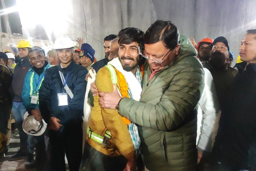 This handout photo provided by the Uttarakhand State Department of Information and Public Relations shows Pushkar Singh Dhami, right, Chief Minister of the state of Uttarakhand, greeting a worker resc ...