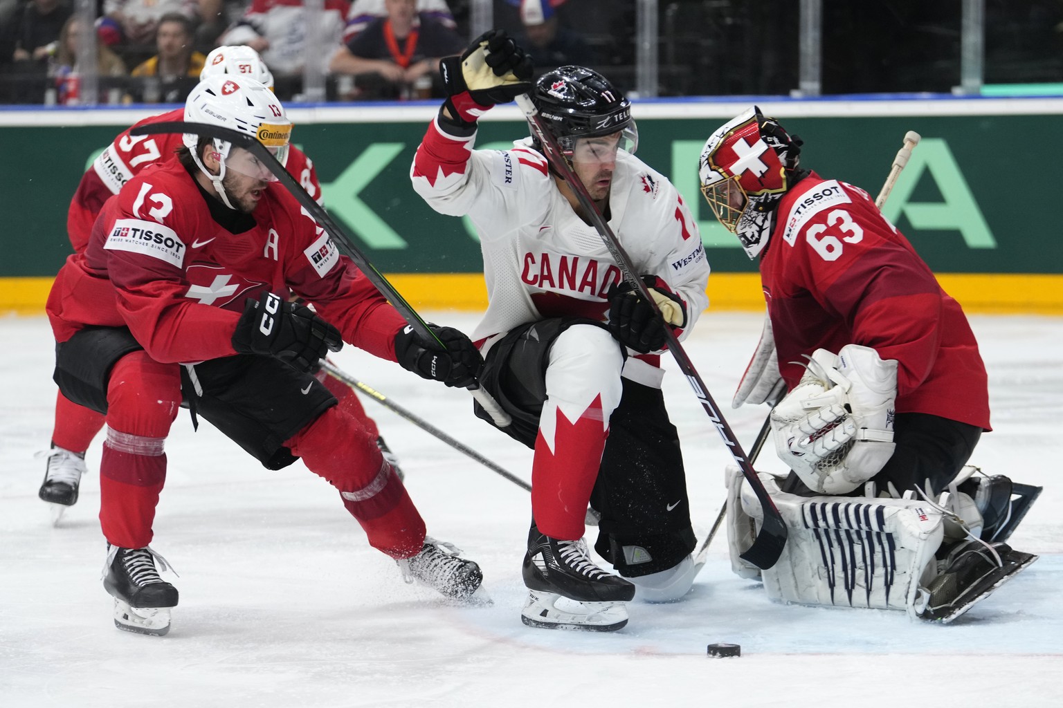 Switzerland&#039;s goalkeeper Leonardo Genoni, right, makes a save as Switzerland&#039;s Nico Hischier, left, challenges Canada&#039;s Jack Mcbain during the semifinal match between Canada and Switzer ...