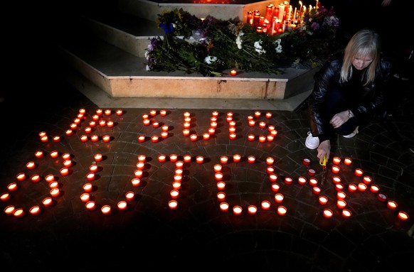 An Ukrainian woman who lives in Lebanon, lights candle with words: &quot;I am Butcha&quot; to commemorate the civilians who were killed during the Russian occupation in Bucha, outside the Ukrainian em ...
