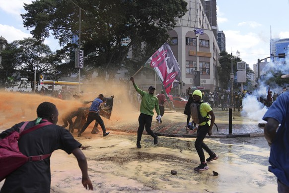 FILE - Protesters scatter as Kenya police spray a water canon at them during a protest over proposed tax hikes in a finance bill in downtown Nairobi, Kenya on June. 25, 2024. The ballooning debt in Ea ...