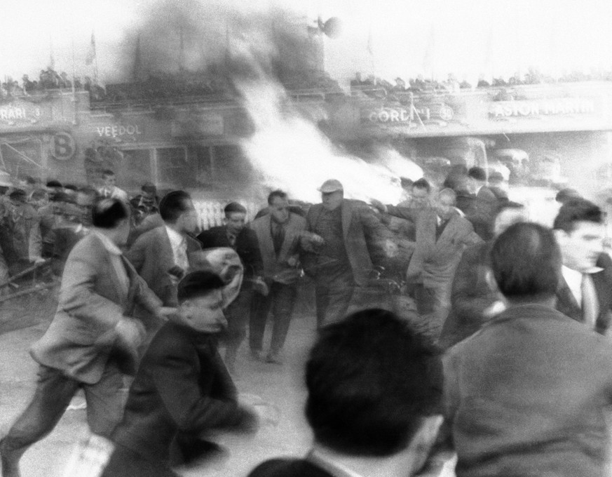 Auto racing fans run from burning car in background after it crashed during 24-hour endurance race at Le Mans, France on June 11, 1955. Over 70 persons were killed by flying pieces of racer driven by  ...