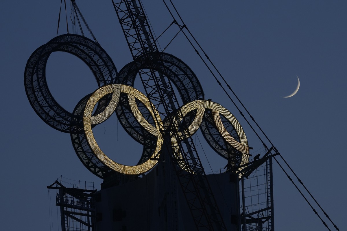 A worker labors to assemble the Olympic Rings onto of a tower on the outskirts of Beijing, China, Wednesday, Jan. 5, 2022. Beijing will host the Winter Olympics in a month's time, making it the w ...
