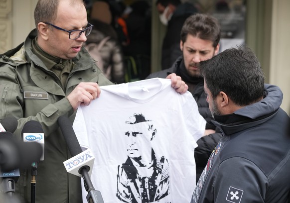 The Mayor of Przemysl, Wojciech Bakun, left, holds up a t-shirt with the likeness of Russian President Vladimir Putin as Italy&#039;s League Party leader, Matteo Salvini, right, speaks with journalist ...
