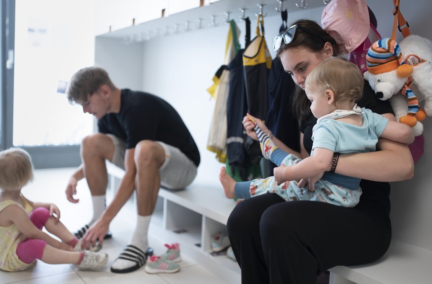 THEMENBILD ZUR LANCIERUNG DER KITA-INITIATIVE --- Betreuungspersonal hilft Kleinkindern beim Anziehen der Schuhe und Sonnenschutzkleidung, bevor es zum Spielen in den Aussenbereich der Kita 6a der Sti ...