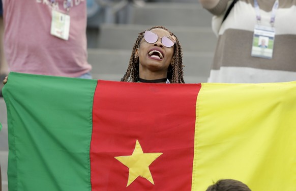 FILE - In this Sunday, June 25, 2017 file photo, a Cameroon fan holds a flag prior to the Confederations Cup, Group B soccer match between Germany and Cameroon, at the Fisht Stadium in Sochi, Russia.  ...