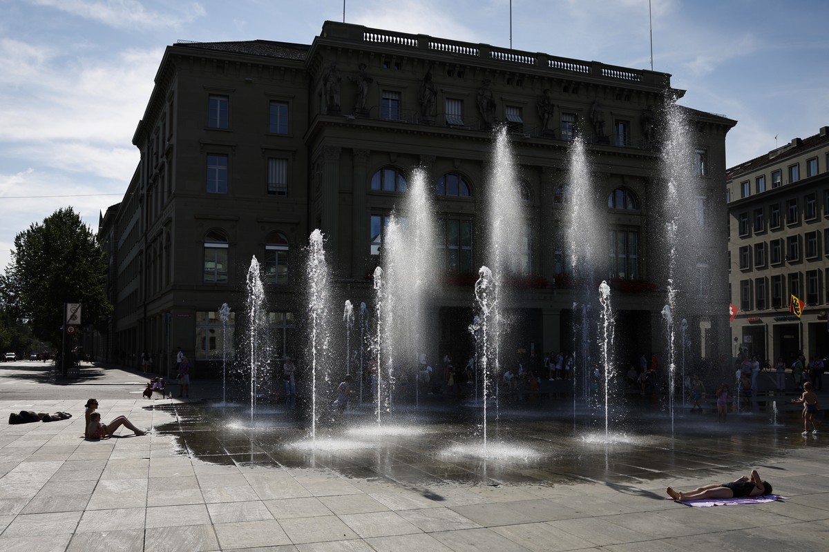 Kinder und Erwachsene geniessen die Abkuehlung beim Wasserspiel auf dem Bundesplatz, am Donnerstag, 25. Juli 2024 in Bern. (KEYSTONE/Peter Klaunzer)