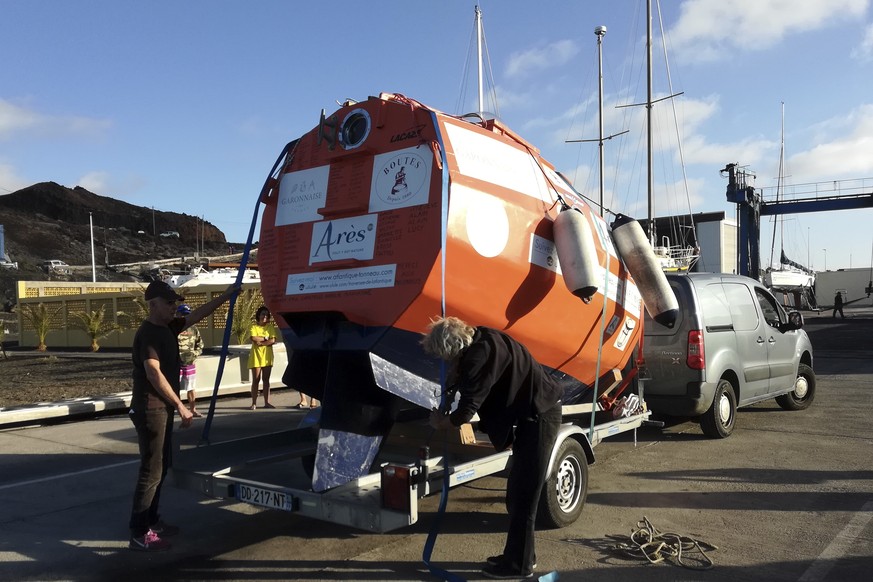 In this photograph taken Saturday Dec. 22, 2018, Frenchman Jean-Jacques Savin, 71-year-old, left, unloads his 3-metre (10-foot) long, 2.1-metre (7-foot) wide resin-coated plywood capsule, which will u ...