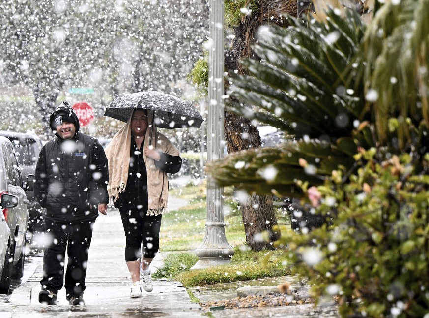Luie Rivera and Gabriela Soto enjoy a walk as snow falls at approximately the 1,700 foot level in their Fontana, Calif., neighborhood of Hunters Ridge on Saturday, Feb. 25, 2023. (Will Lester/The Oran ...