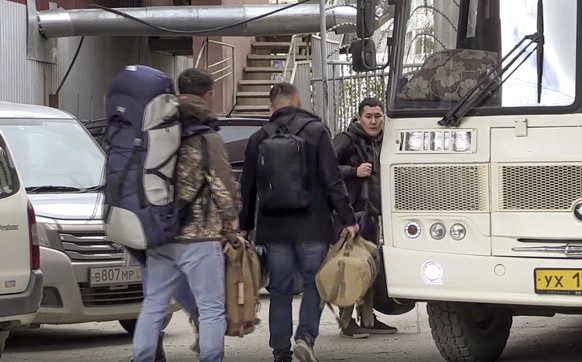 In this image taken from video, Russian draftees walk to take a bus to be sent further to the military units of the Eastern Military District, in Yakutsk, Russia, Friday, Sept. 23, 2022. Mobilization  ...