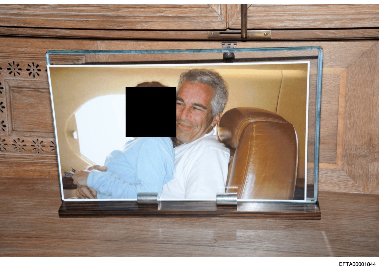 This redacted photo released by the U.S. Department of Justice shows a framed photograph of Jeffrey Epstein with a person on his lap, documented on Aug. 12, 2019, during a search of his home on Little ...
