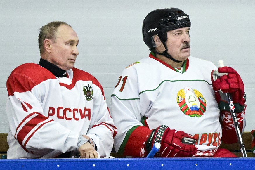 Russian President Vladimir Putin, left, and Belarusian President Alexander Lukashenko take a pause during the Night Hockey League match following their talks in Strelna, outside St. Petersburg, Russia ...