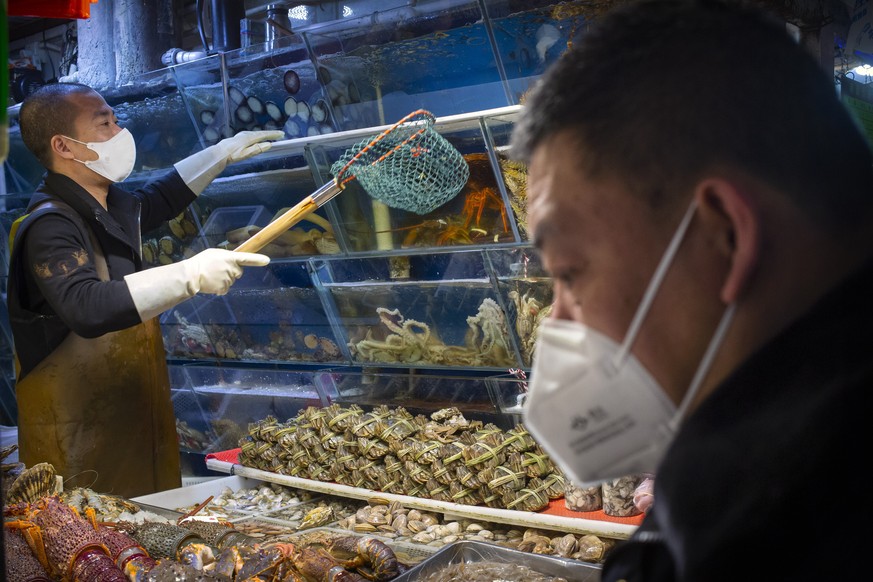 A customer wears a face mask as he shops for seafood at a market in Beijing, Saturday, March 14, 2020. The United States declared a state of emergency Friday as many European countries went on a war f ...