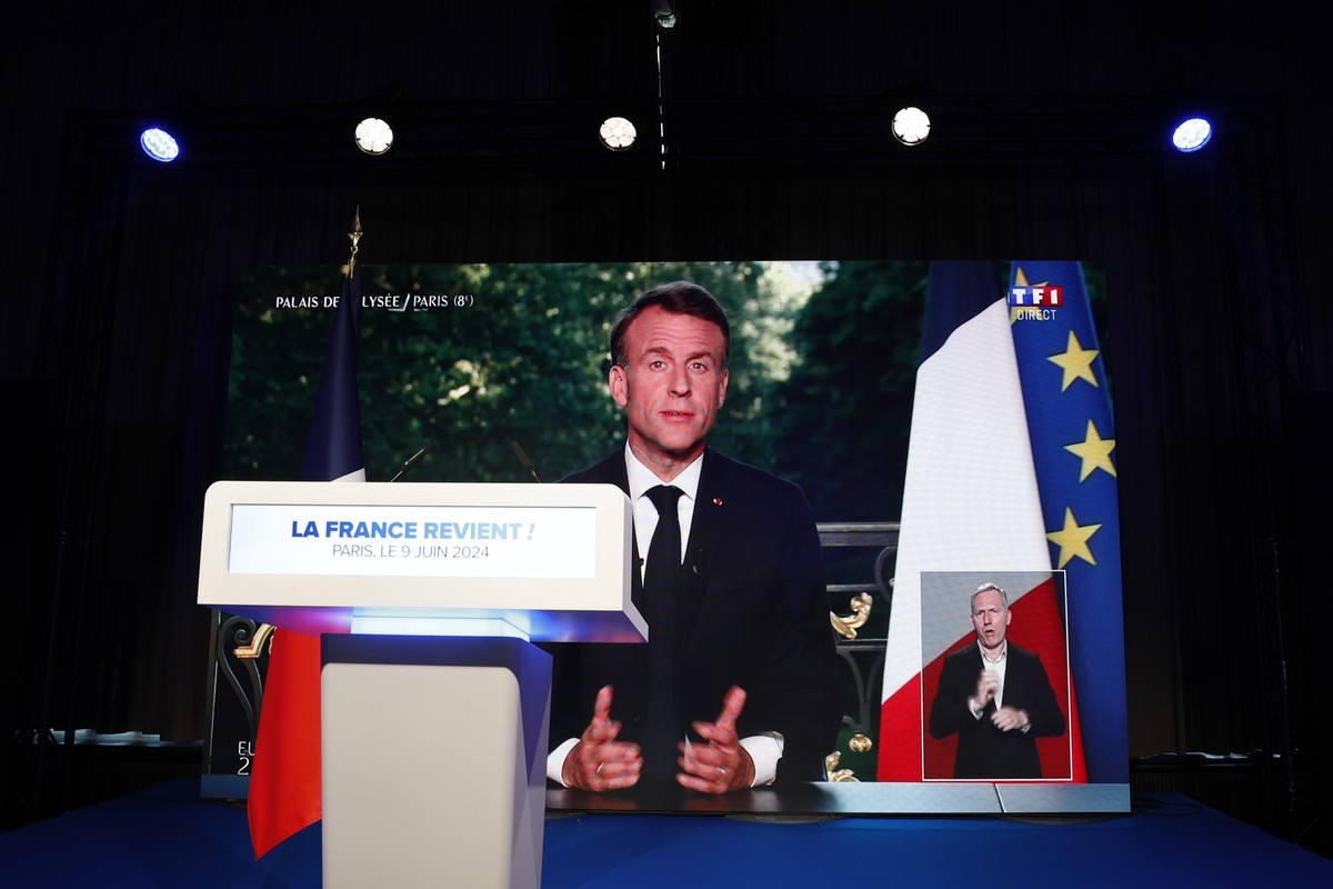 epa11400684 French President Emmanuel Macron is displayed on a large screen during a televised address to the nation, at the electoral party of the French right-wing party National Rally (Rassemblemen ...