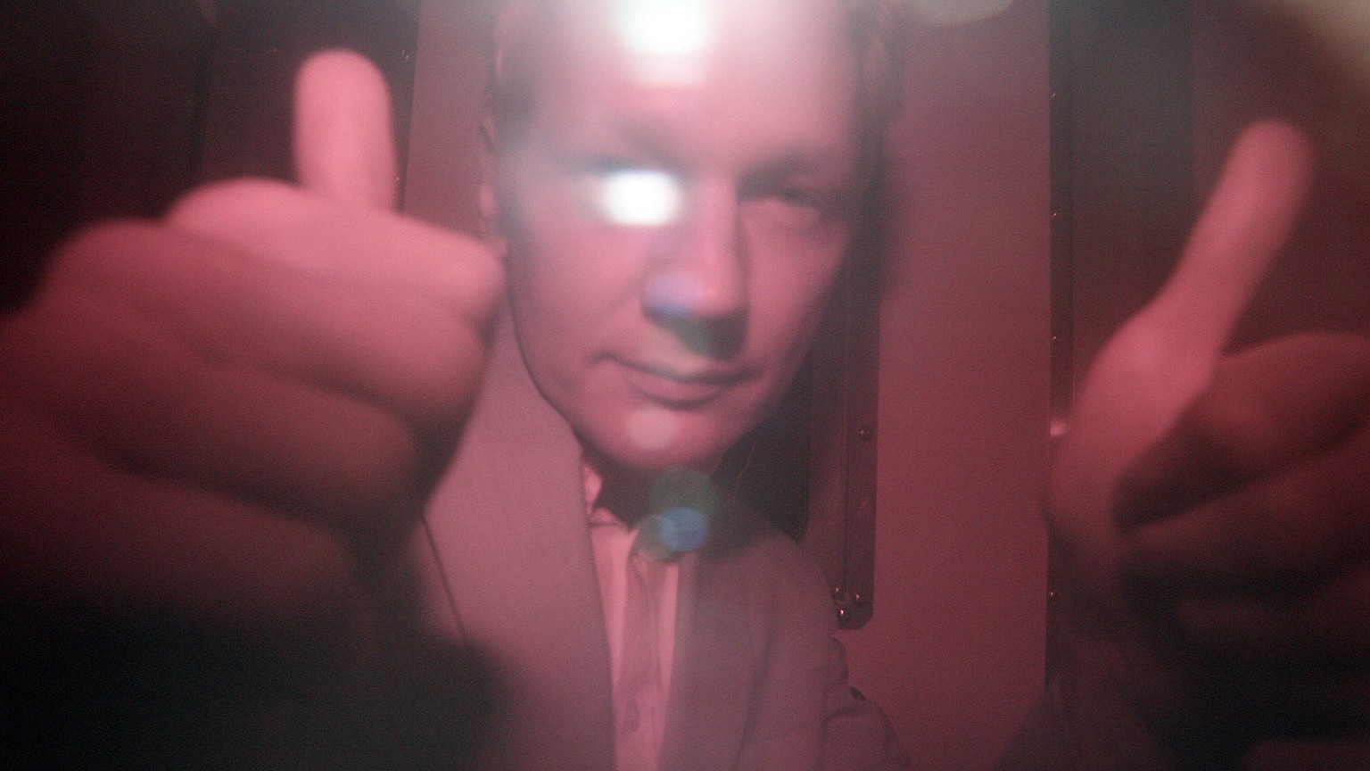 FILE - In this Tuesday, Dec. 14, 2010 file photo, WikiLeaks founder Julian Assange reacts behind the heavily tinted window of a police van as he arrives at Wandsworth Prison in London. Police in Londo ...