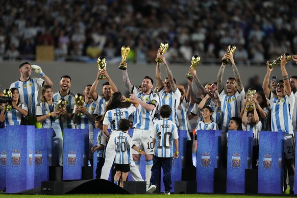 Argentina&#039;s Lionel Messi, center, raises the winning team replica of the FIFA World Cup trophy during a celebration ceremony for local fans after an international friendly soccer match against Pa ...
