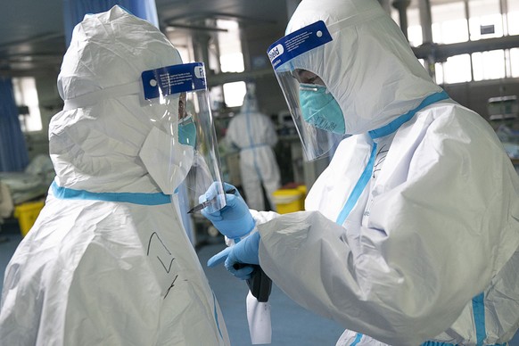 In this photo released by China&#039;s Xinhua News Agency, a medical worker writes their colleague&#039;s name on a protective suit to aid in identification as they work at Zhongnan Hospital of Wuhan  ...