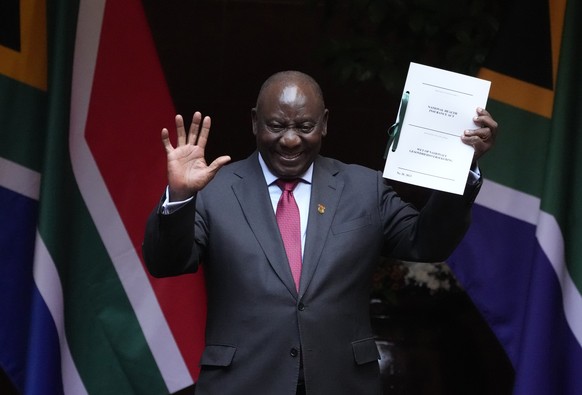 File ? South African President Cyril Ramaphosa shows the signed bill for National Health Insurance signed into law in Pretoria, South Africa, Wednesday, May 15, 2024. Today the ruling African National ...