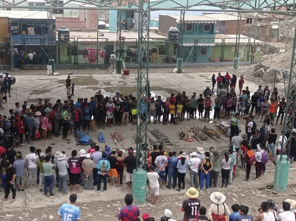Residents stand around the bodies of persons who perished in recent landslides in Camana, Peru, Monday, Feb. 6, 2023. According to a preliminary report issued by Civil Defense, more than 30 people die ...