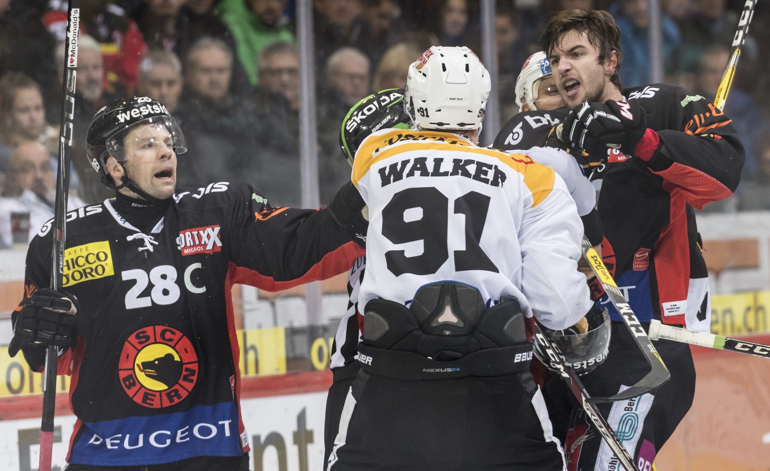 HC Lugano Stuermer Julian Walker, Mitte, laesst sich auf einen Faustkampf ein gegen SC Bern Stuermer Alain Berger, rechts, und Martin Pluess, im Eishockey Meisterschaftsspiel der National League A zwi ...